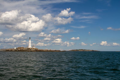 Lighthouse by sea against sky