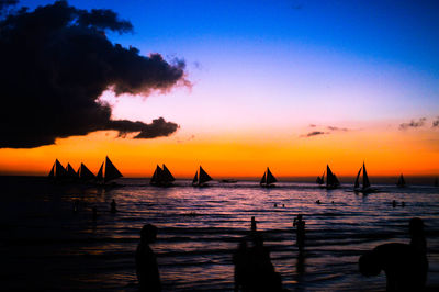 Silhouette man in sea against sky during sunset