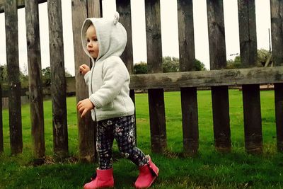 Full length of cute boy standing on fence