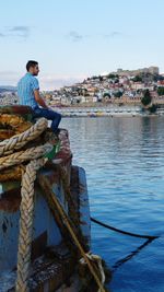 Man sitting on boat in sea against sky