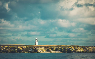 Lighthouse by sea against sky