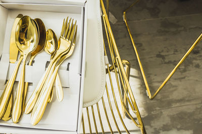 High angle view of golden cutlery in box on table