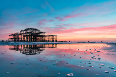 Scenic view of beach against sky at sunset