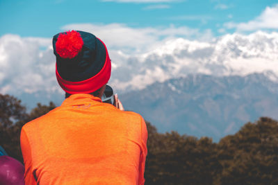 Rear view of woman looking at mountains against sky