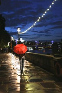 Rear view of woman walking in illuminated city