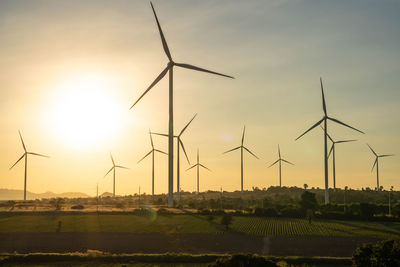 Windmill on field against sky during sunset