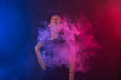 Young man smoking against black background