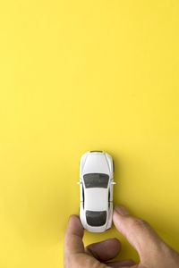 Close-up of person hand holding eyeglasses against yellow background