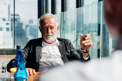 Portrait of man sitting in glass