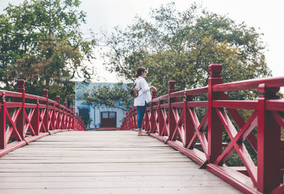 Rear view of man on footbridge against sky