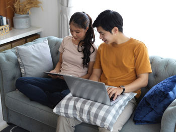 Couple using laptop while sitting at home