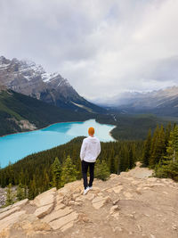 Rear view of man standing on mountain against sky
