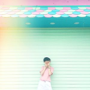 Full length of colorful woman standing in front of multi colored wall