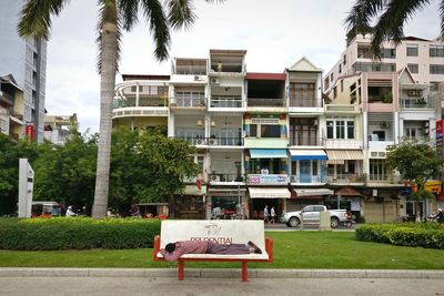 Chairs and tables on street by buildings against sky