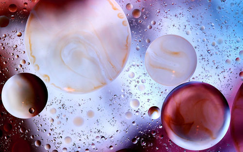 Bubbles with brown streaks between small drops abstractly against a brightly lit background