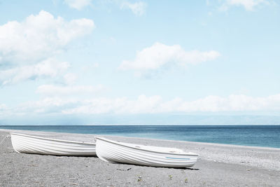 Two white boats on the pebble beach. tourist season on the mediterranean sea. sicily. ionian sea