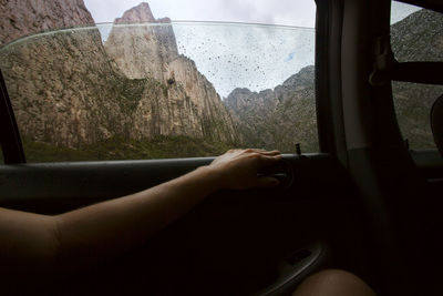 Cropped image of person sitting in car with mountains in background person