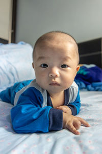 Portrait of cute baby lying on bed at home