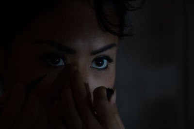 Close-up portrait of woman applying makeup