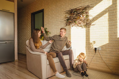 Side view of woman sitting on sofa at home