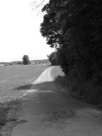 Road amidst field against clear sky