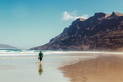 Rear view of man walking on shore at beach