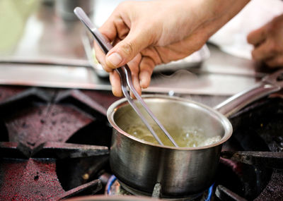 Cropped hands of person preparing food on stove
