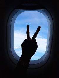 Cropped hand of person gesturing against airplane window