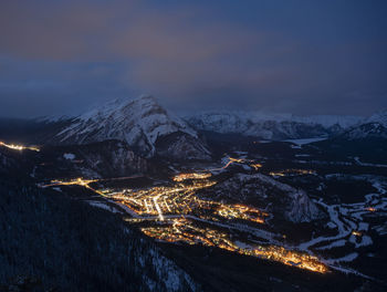 Aerial view of illuminated snowcapped mountains against sky at night