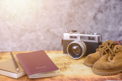 Close-up of camera with passport and shoes on table