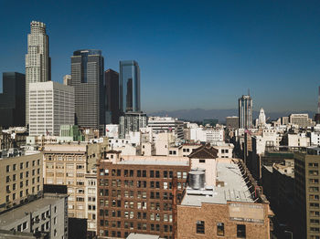 Buildings in city against clear blue sky