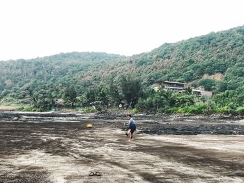 Man walking on mountain against clear sky