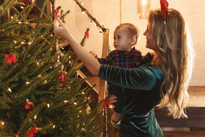 Rear view of woman standing by christmas tree