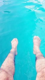 Low section of man relaxing in swimming pool