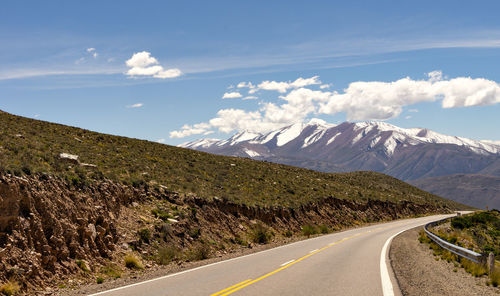 Road by mountains against sky