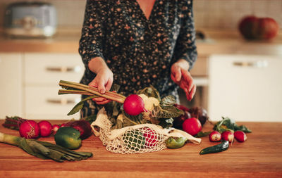 Midsection of woman with fruits on table at home