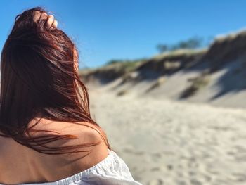 Rear view of woman with hand in hair at beach