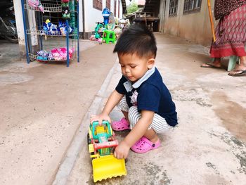 Close-up of boy playing with toy while crouching on footpath