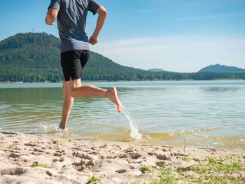 Low section of man on lake against sky