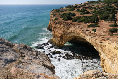 Rock of benagil by sea against sky