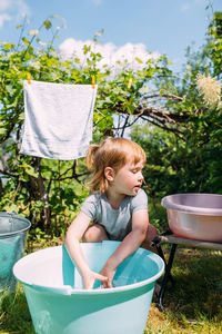 Little preschool girl helps with laundry. child washes clothes in garden