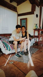 Full length of smiling young couple sitting at home