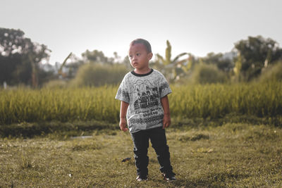 Portrait of toddler boy standing on field