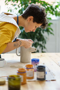 Young female ceramist decorate potter jug after burning. artisan paining pottery in ceramic workshop