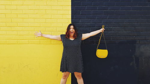 Full length of young woman standing in front of wall