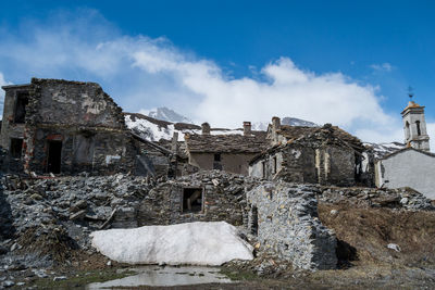 Abandoned houses against sky in winter