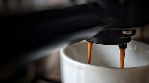 Close-up of coffee pouring in cup