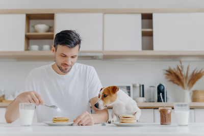 Dog looking at man having breakfast