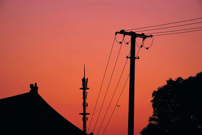 Low angle view of silhouette electricity pylon against romantic sky