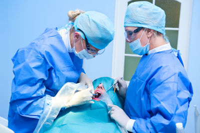 Doctors performing dental implantation in operating room